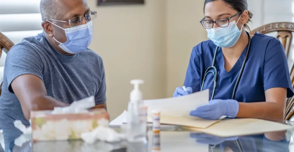 Nurse in mask looking over paper work with elderly man in mask.