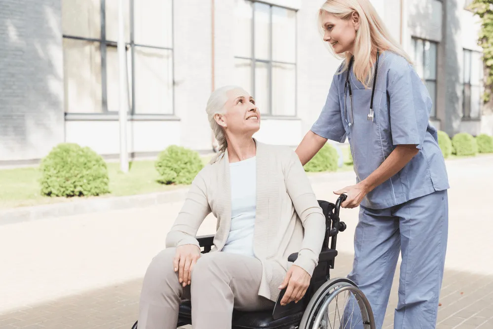 Nurse cares for elderly patient woman in a wheel chair.