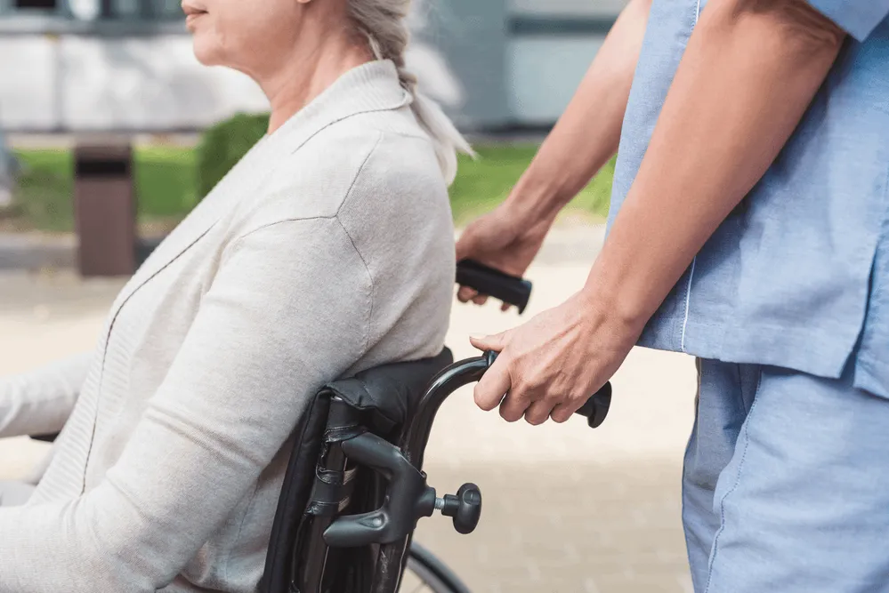 A nurse pushing an elderly woman in a wheelchair