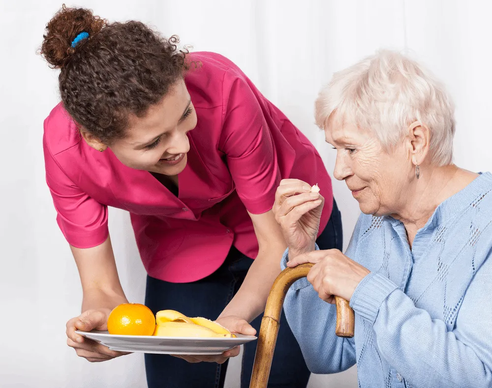 A nurse bringing an elderly woman lunch.