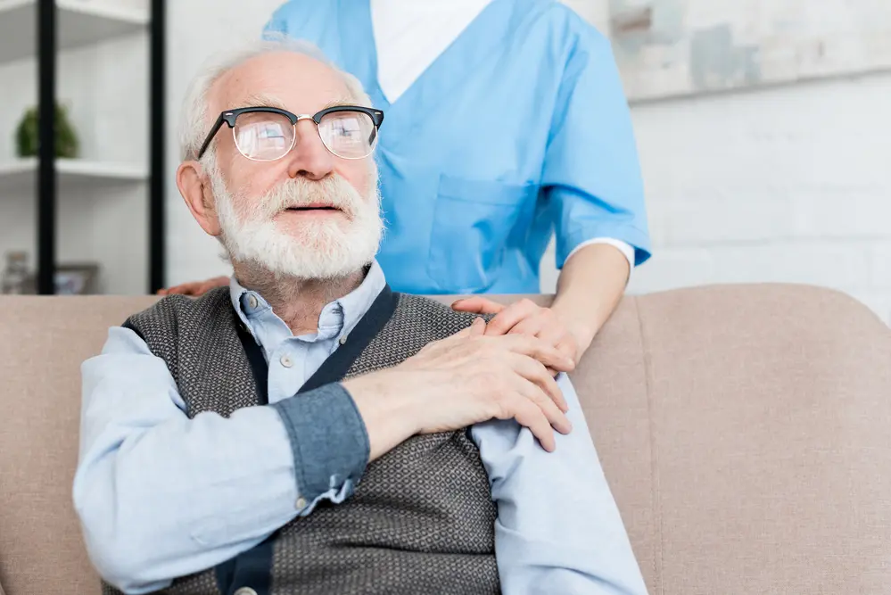 A nurse with her hand on an elderly man's shoulder.