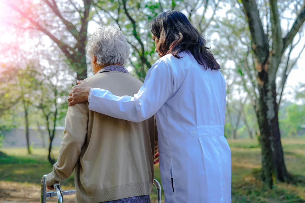 A home nurse taking an elderly woman for a walk.
