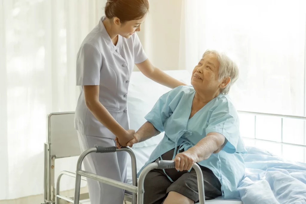 Home care nurse helping an elderly woman stand up.
