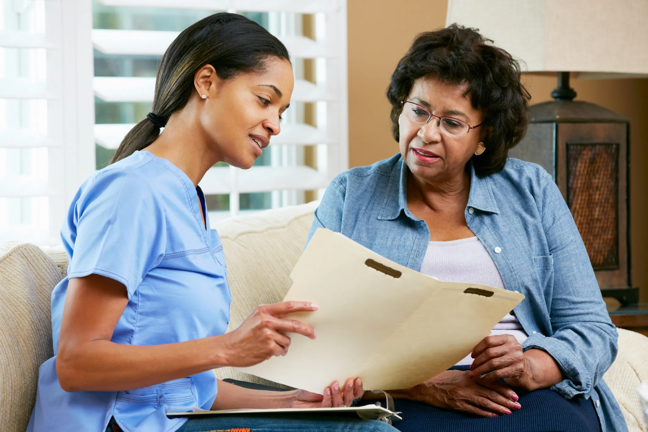 Black female nurse discussing a health plan with elderly woman.