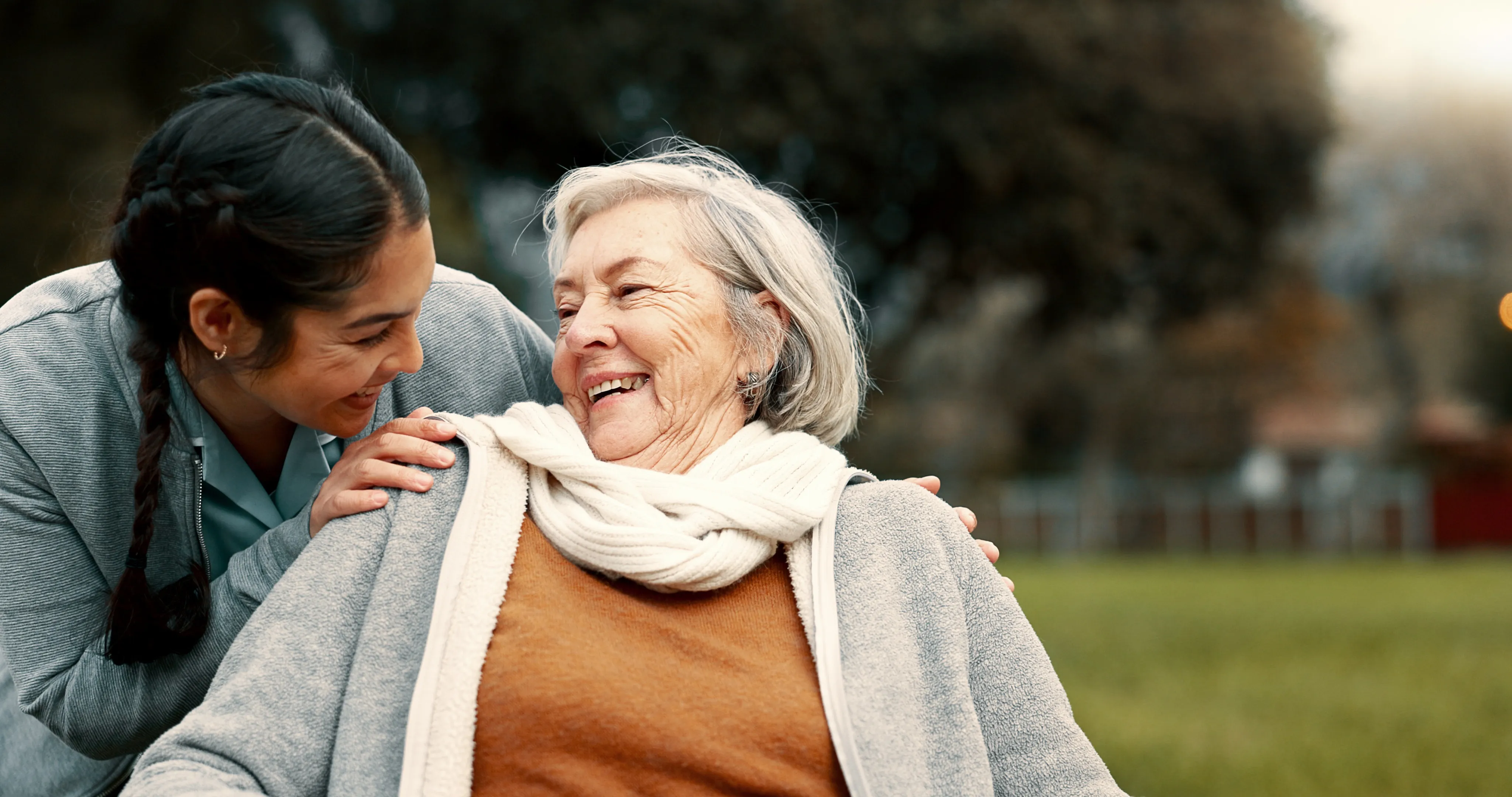 A nurse and elderly woman smiling and talking.