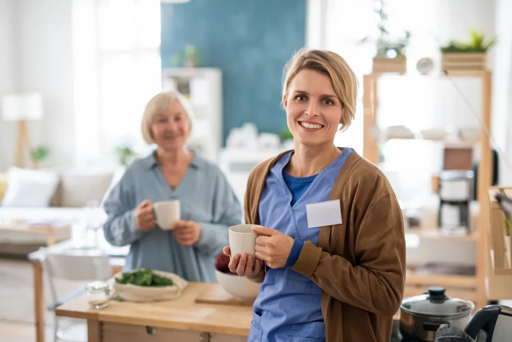 home care aide smiling and drinking tea with a patient.