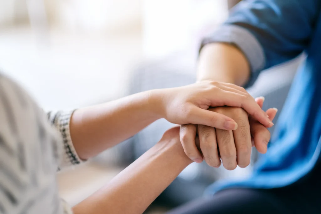 A close up of a home health aide holding a patient's hand.