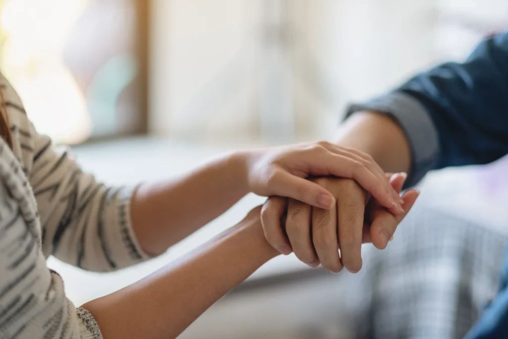 A close up of a younger woman holding the hand of an older woman.