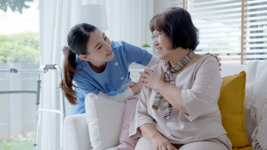 A home health aide with her arms around an elderly woman.
